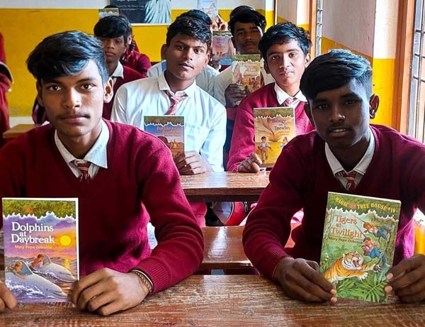 Boys show recent gifts of English language story books.